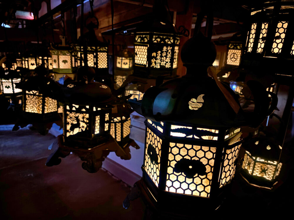 春日大社・大宮・藤浪之屋内の暗闇の中に灯された灯籠たち