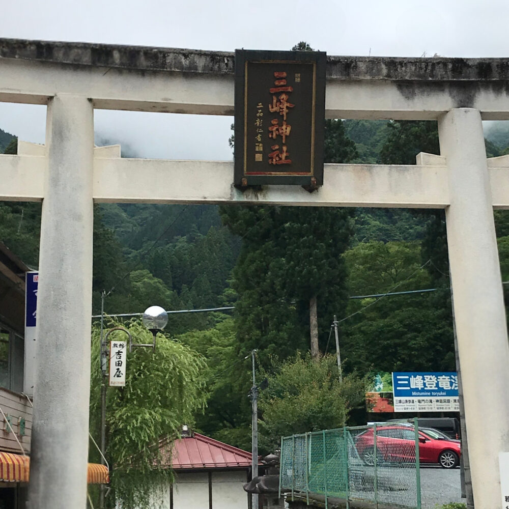 三峯神社の白い鳥居と山あいの参道入口