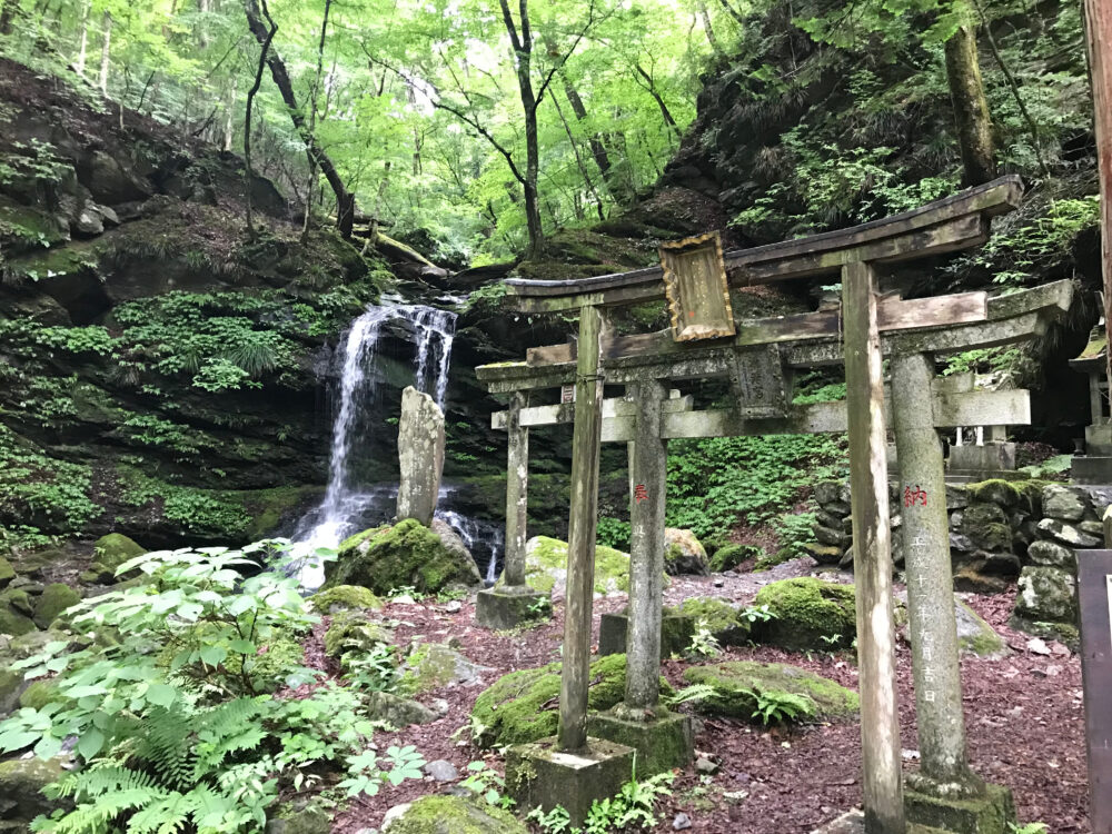 鳥居越しに見る清浄の滝と苔むした岩場