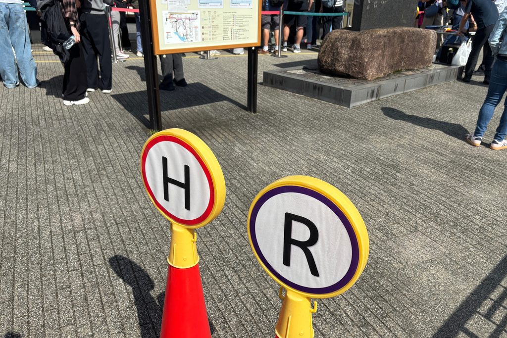 箱根湯本駅のバス停に並ぶ人々と、乗り場を示すH・Rの標識